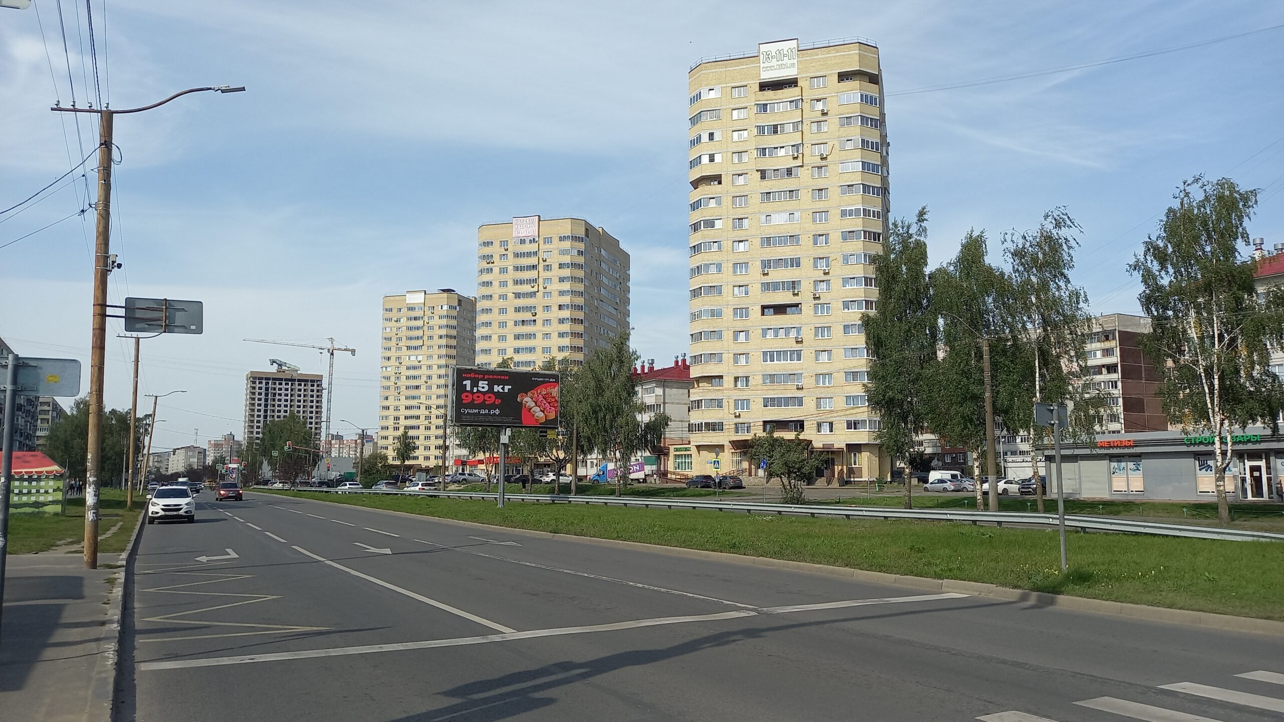 Городская улица в Ярославле с автомобилями, жилыми высотками и рекламным щитом