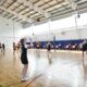 Участницы играют в волейбол в спортивном зале