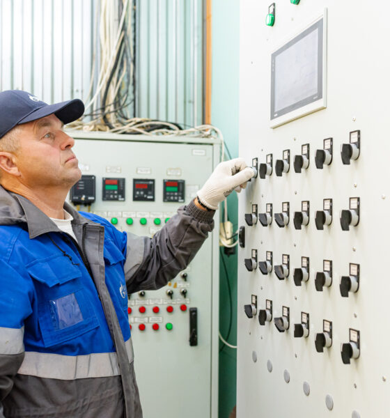Сотрудник газовой службы настраивает электрощит управления оборудованием