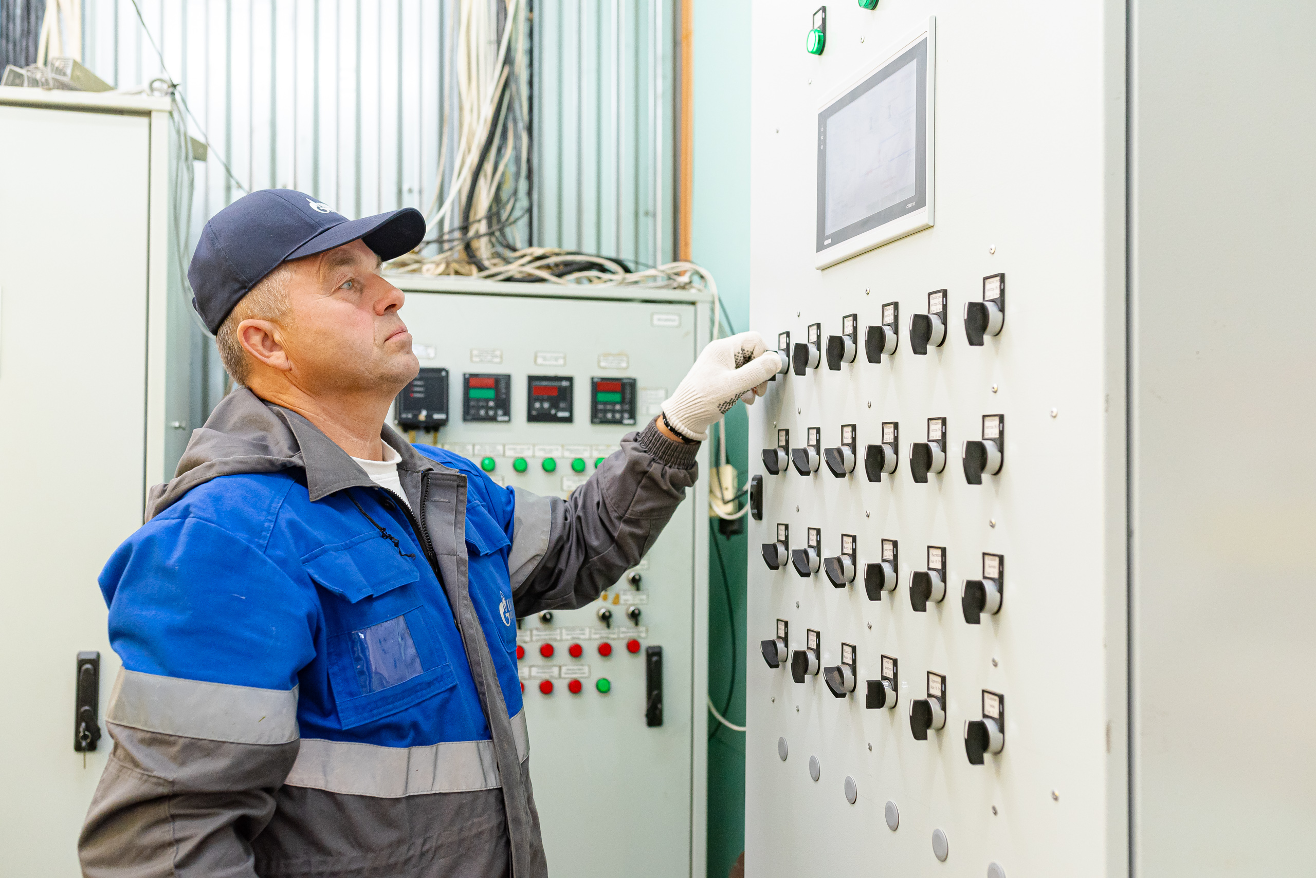 Сотрудник газовой службы настраивает электрощит управления оборудованием
