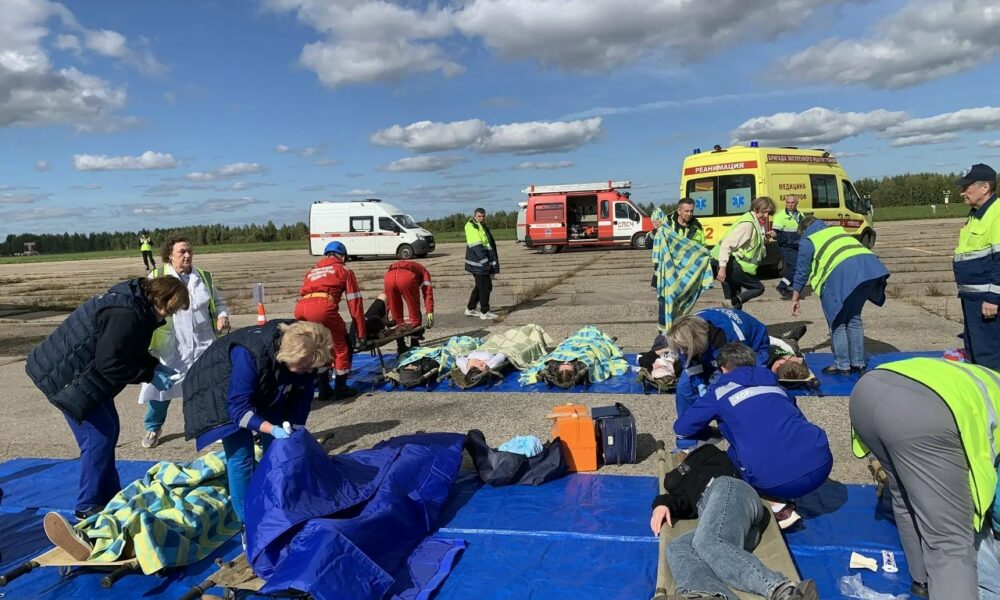 Учения спасателей на аэродроме: медики оказывают помощь пострадавшим рядом с машинами скорой помощи
