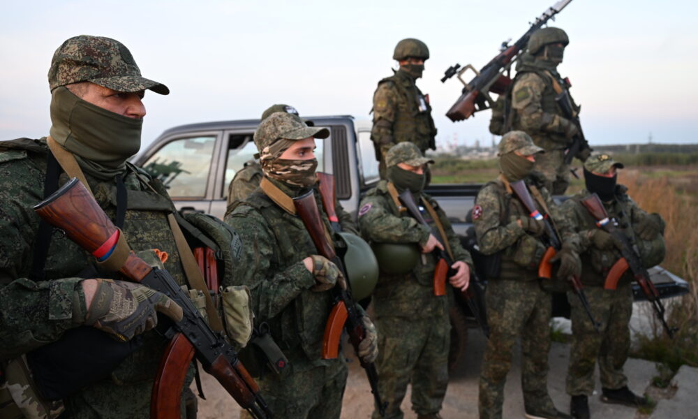 Вооружённые военнослужащие в камуфляже стоят у пикапа в поле