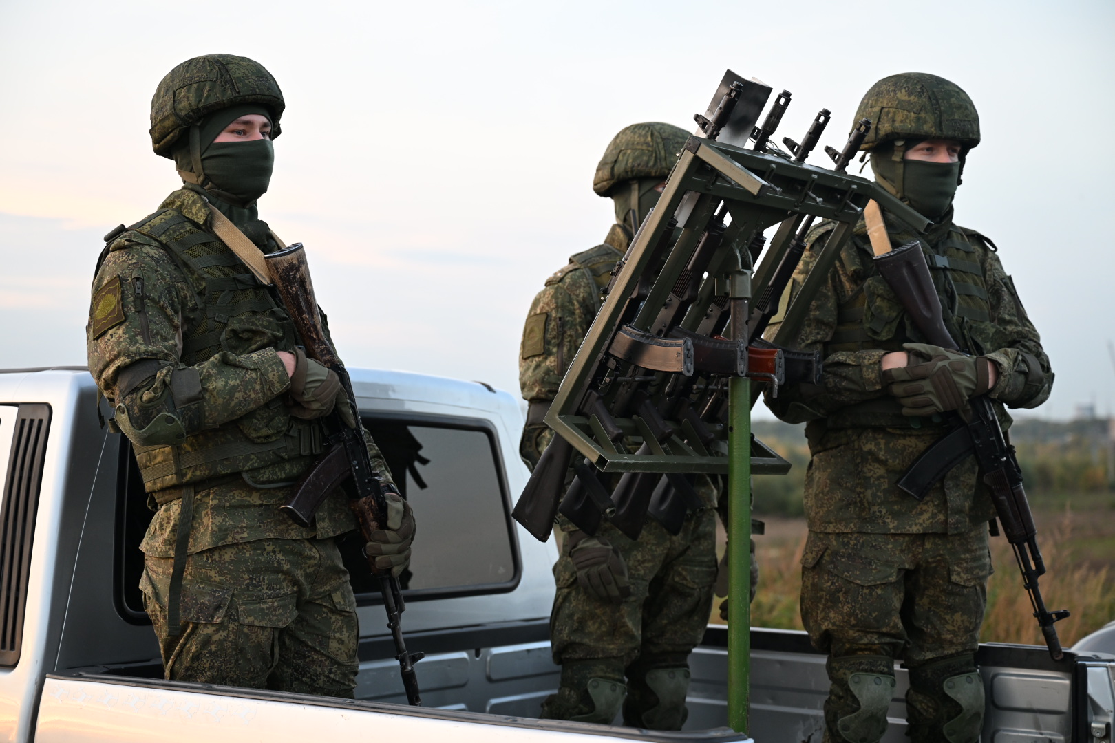 Военнослужащие в камуфляже с автоматами у пикапа и установки для борьбы с БПЛА