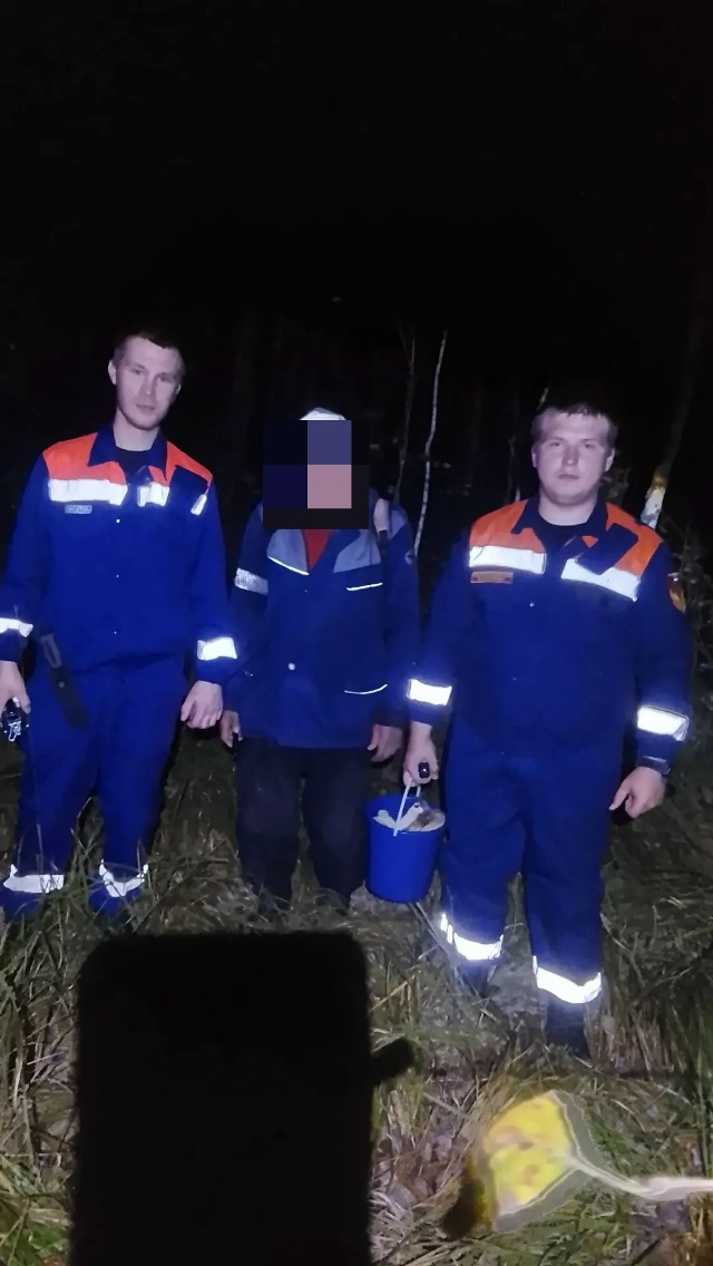 Сотрудники МЧС рядом со спасённым человеком в ночном лесу
