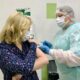 Медработник делает женщине прививку от гриппа в процедурном кабинете