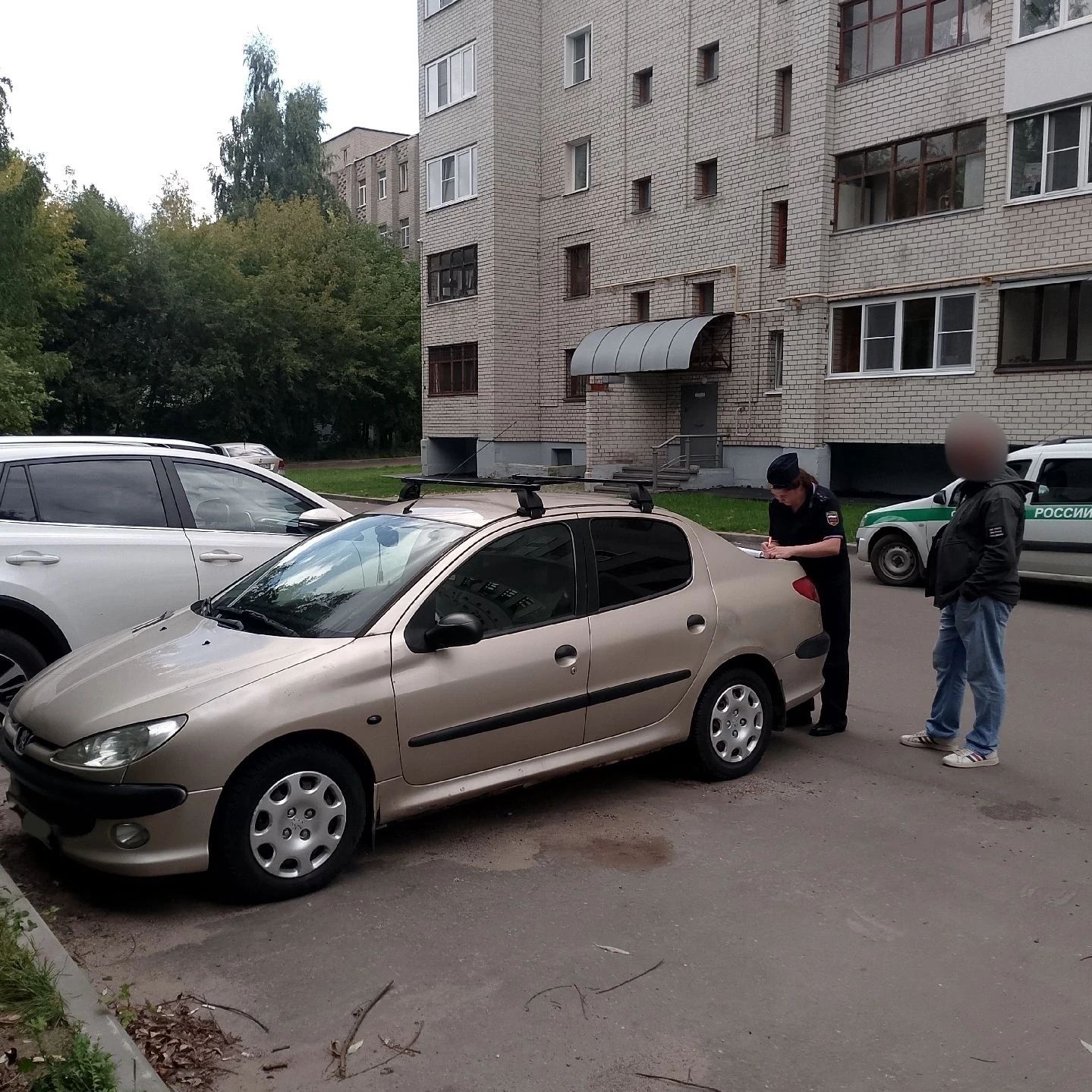 Судебный пристав оформляет арест автомобиля во дворе жилого дома