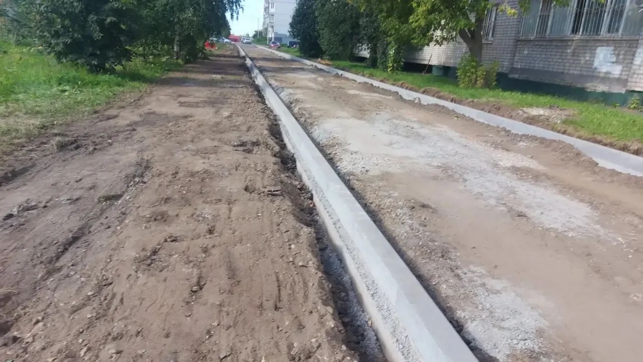 Установка нового бордюра вдоль грунтовой дороги у жилого дома