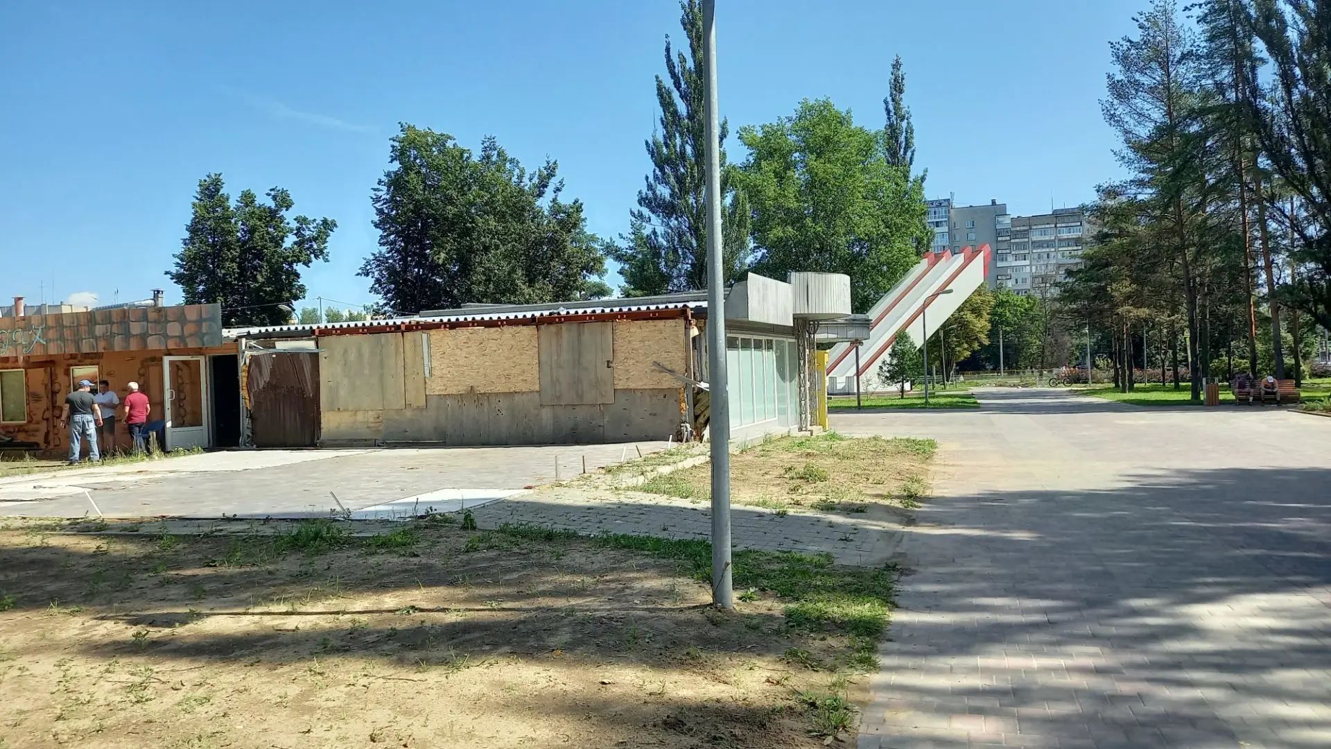 Заколоченный павильон у пешеходной дорожки в городском парке
