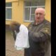 Мужчина держит куницу, укутанную в полотенце, у здания