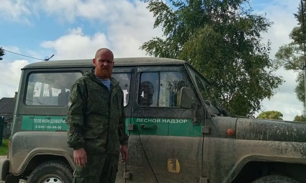 Сотрудник лесного надзора в камуфляже стоит у служебного внедорожника