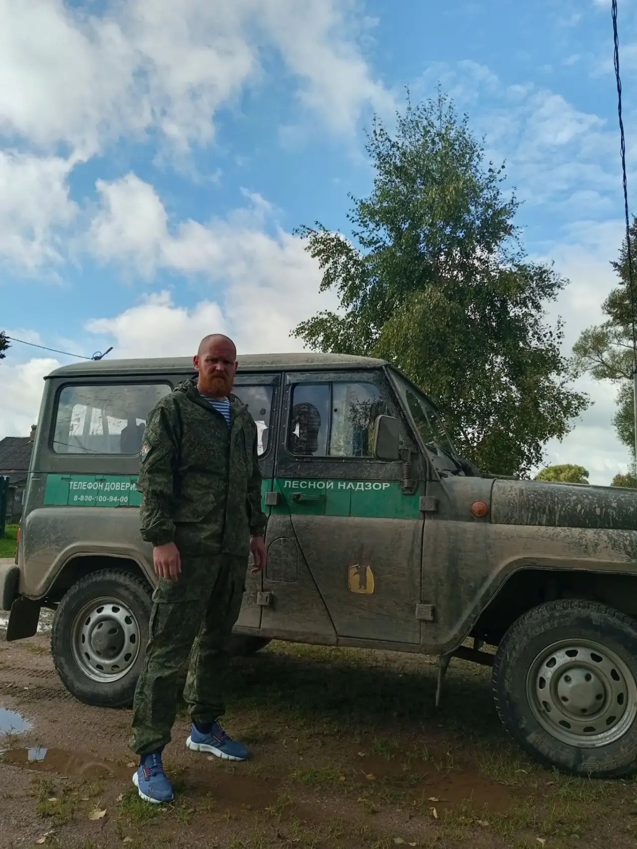 Сотрудник лесного надзора в камуфляже стоит у служебного внедорожника