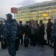 Сотрудники полиции сопровождают группу мужчин с багажом у автобусной остановки аэропорта