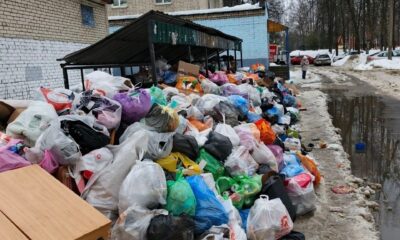 Переполненная мусорная площадка с пакетами отходов у жилого дома зимой