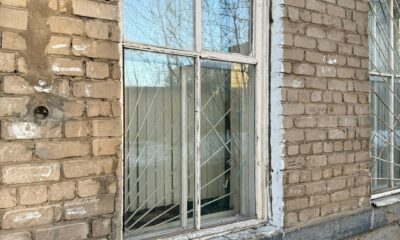 Окно с решёткой на фасаде многоквартирного дома из кирпича