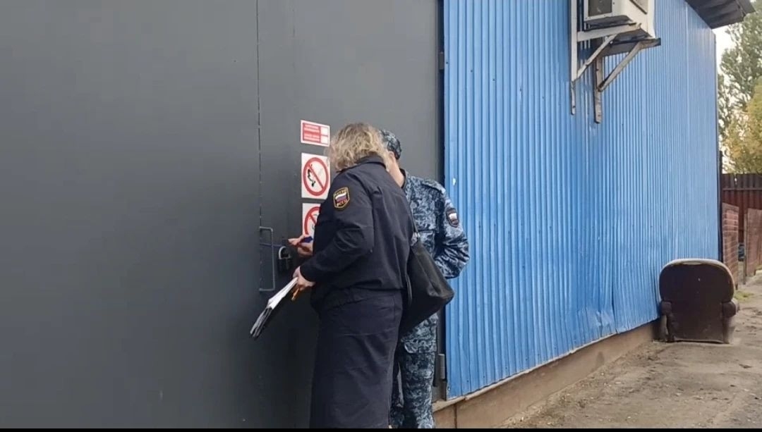 Сотрудники службы у опечатанной двери овощной базы в Ярославле