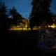 Темный городской парк вечером с силуэтами деревьев и слабо освещенной площадкой вдали