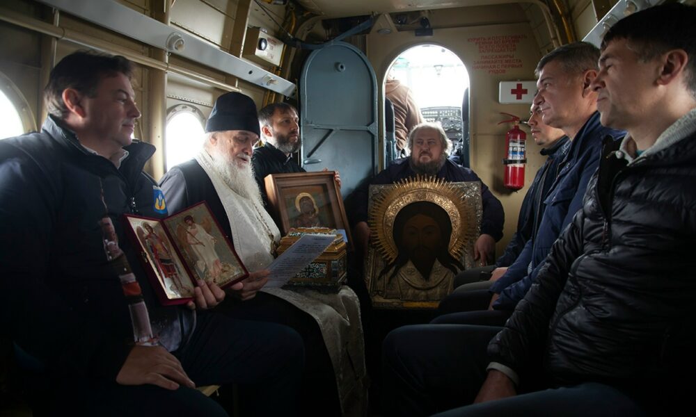 Священник с иконами и участники крестного облета в салоне вертолета