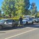 Сотрудник службы судебных приставов стоит у остановленного седана, рядом служебные автомобили