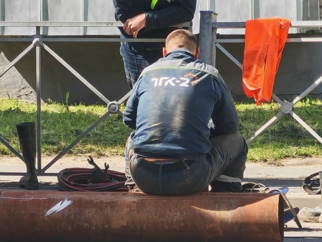 Рабочий ремонтирует теплосети у траншеи