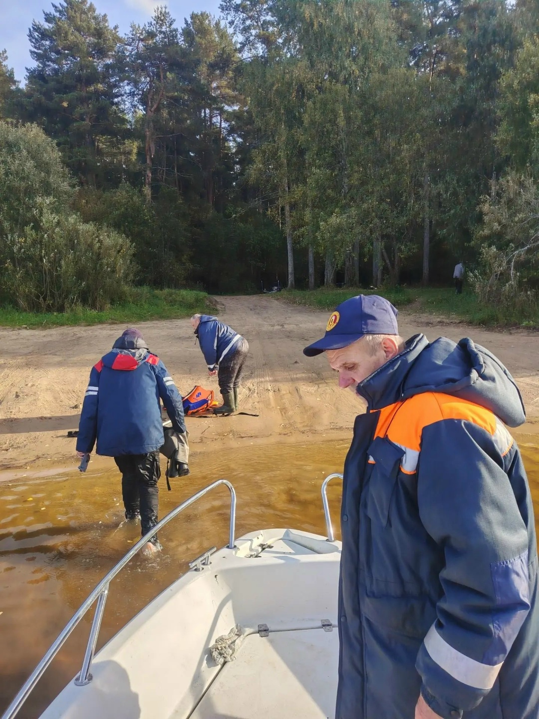 Спасатели помогают людям выйти из лодки на берегу водохранилища