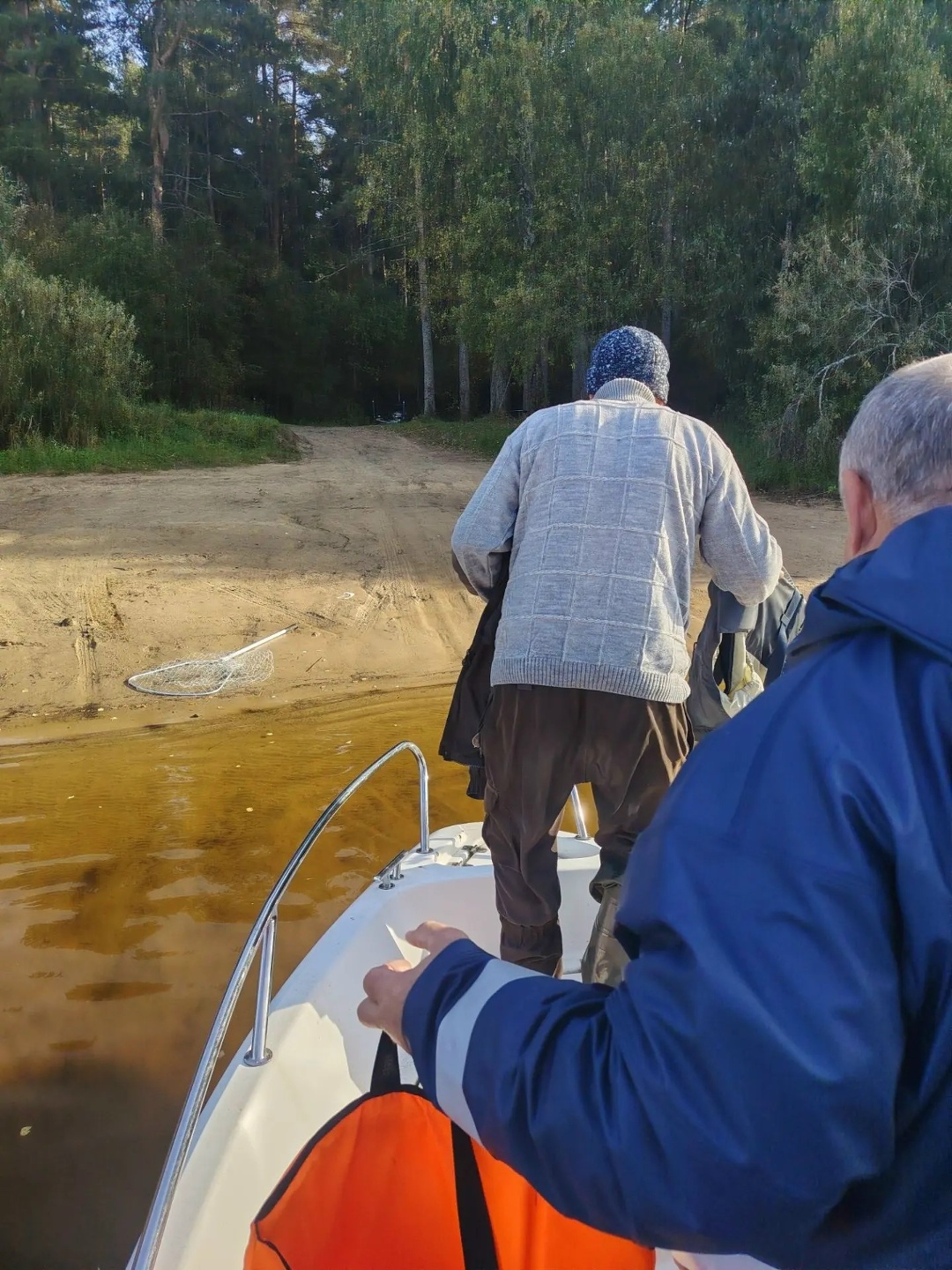 Рыбаки на лодке у лесного берега водохранилища