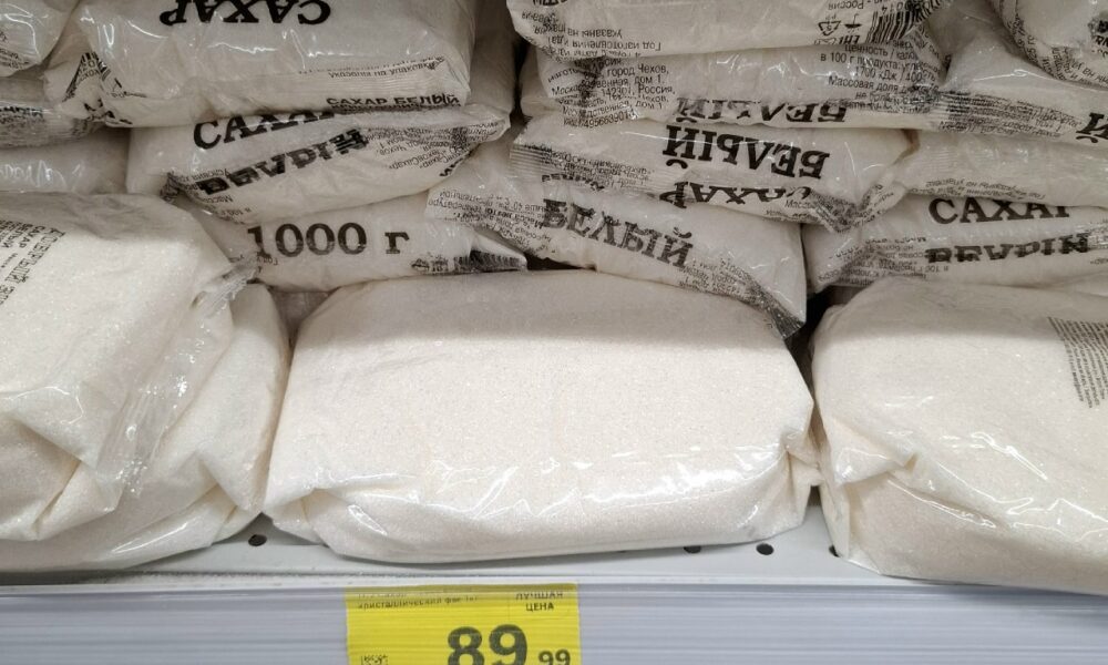Пачки белого сахара по 1 кг на полке магазина с ценником 89,99 рубля
