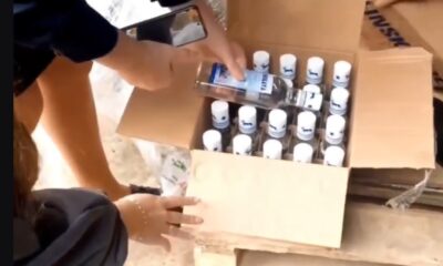 Человек держит бутылку алкоголя над коробкой с бутылками