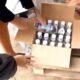 Человек держит бутылку алкоголя над коробкой с бутылками