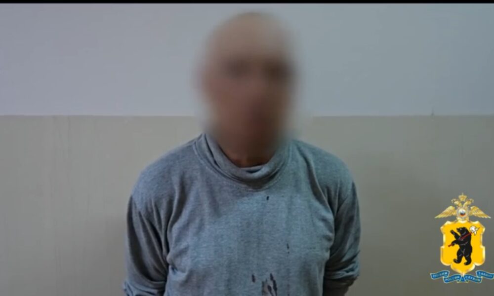 Мужчина с размытым лицом в серой одежде на фоне стены, рядом эмблема полиции