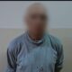 Мужчина с размытым лицом в серой одежде на фоне стены, рядом эмблема полиции