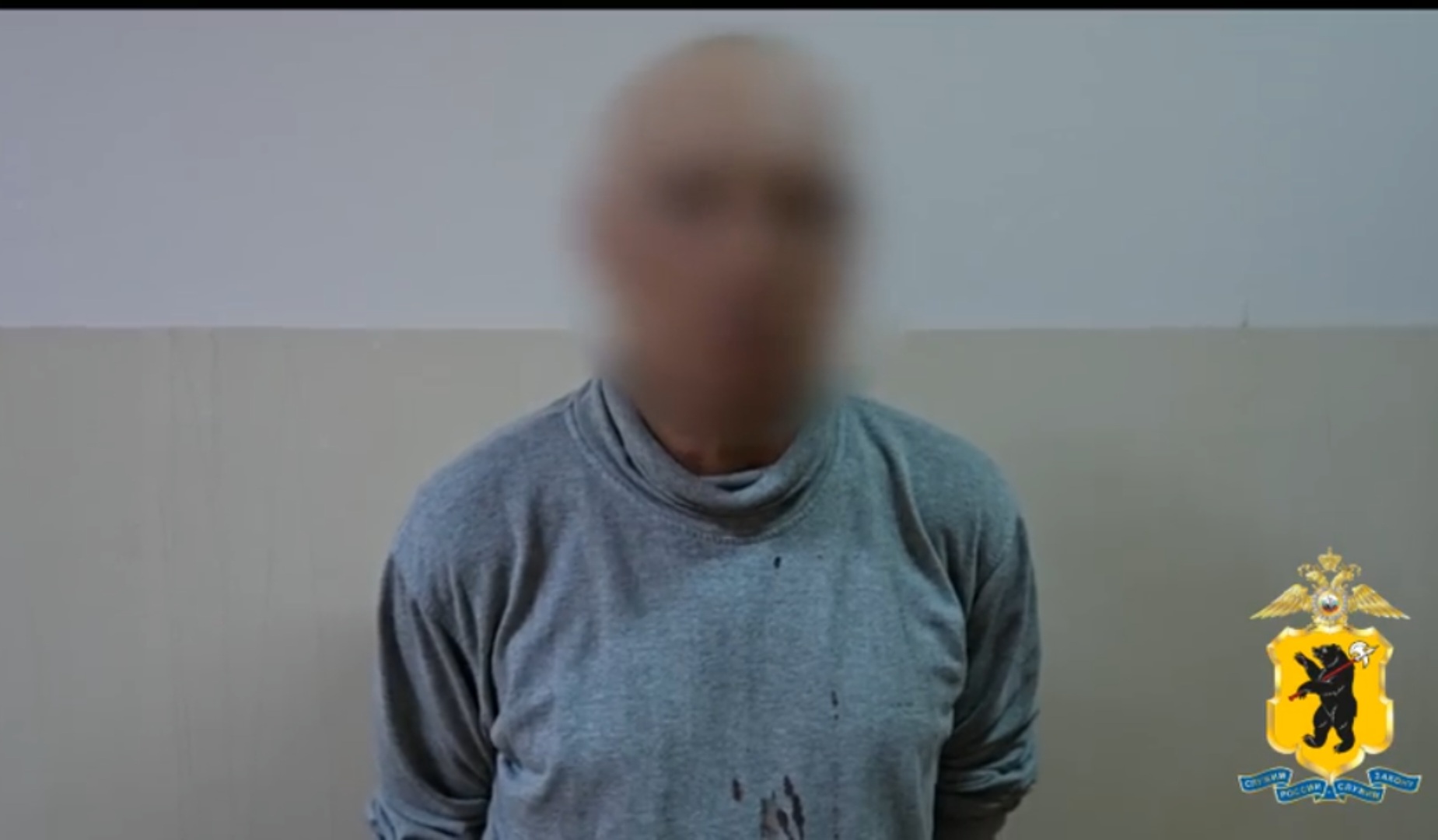 Мужчина с размытым лицом в серой одежде на фоне стены, рядом эмблема полиции