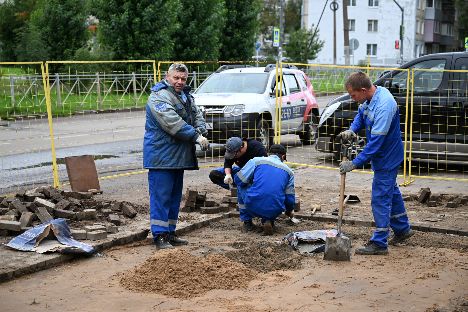 Рабочие ремонтируют тротуарную плитку на городской улице