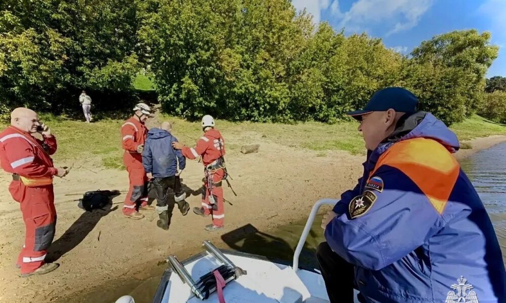 Сотрудники МЧС и рыбак на берегу реки во время спасательной операции