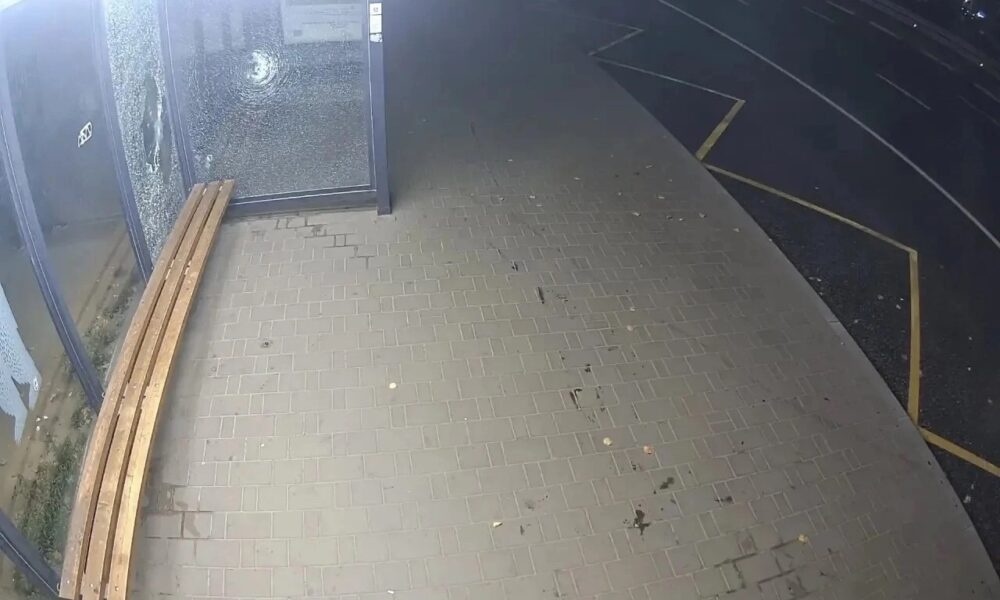 Разбитое стекло на остановке и скамейка у дороги ночью