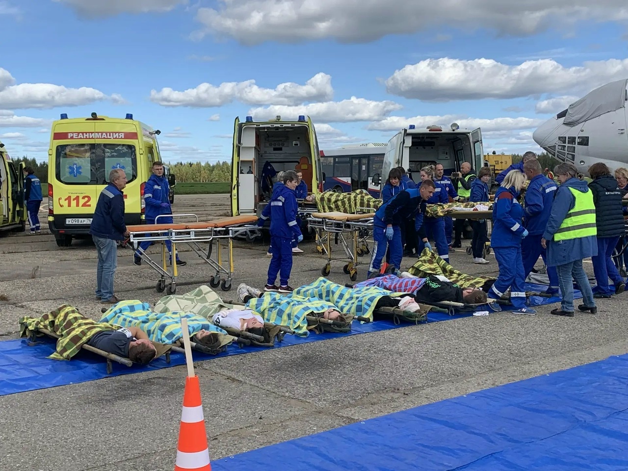 Медики эвакуируют пострадавших на носилках во время учений у самолета