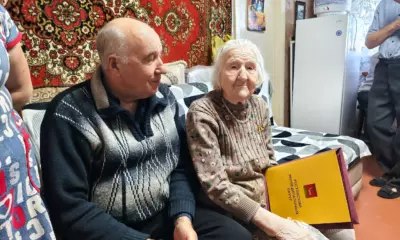 102-летняя жительница Ростовского округа с поздравительным адресом рядом с мужчиной