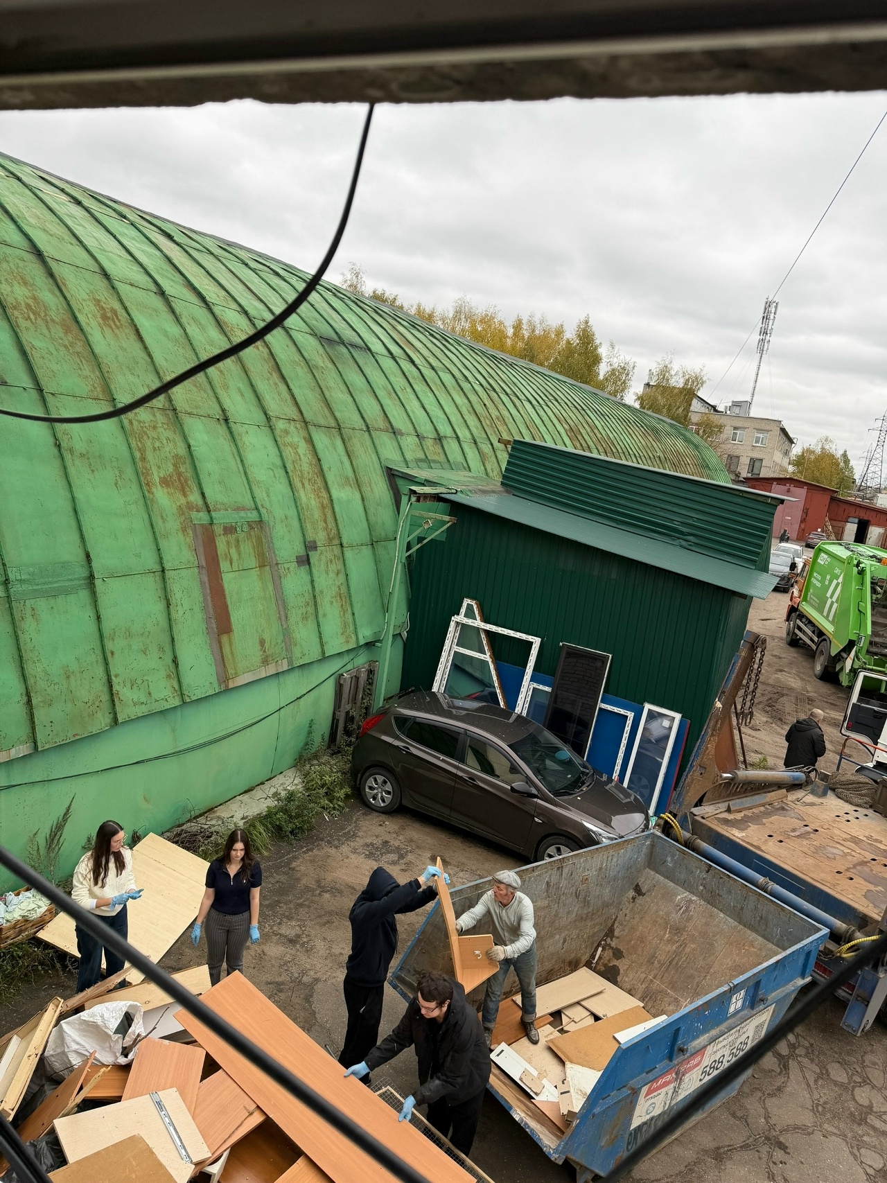 Волонтёры разбирают вещи у зелёного здания кошачьего приюта в Ярославле