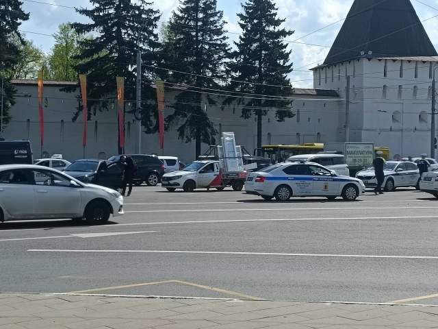 Автомобили ДПС и машины на городской улице у белокаменной стены