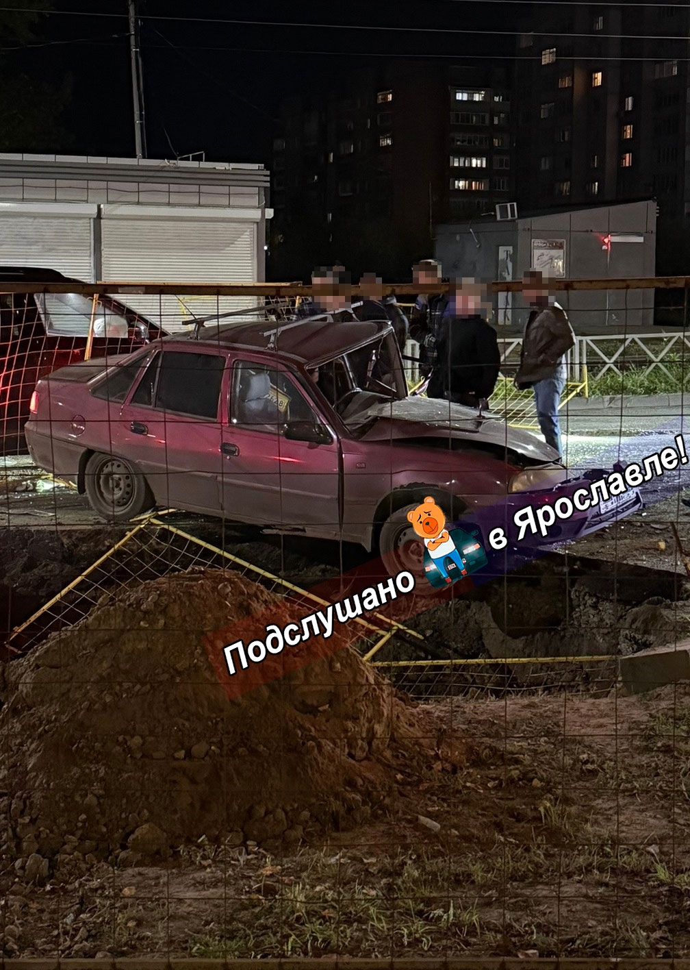 Повреждённый автомобиль у коммунальной ямы за ограждением ночью