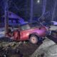 Разбитый красный автомобиль после ДТП врезался в дерево ночью