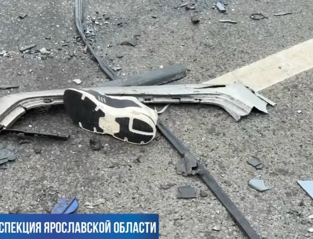 Кроссовок рядом с обломками автомобиля на дороге после ДТП