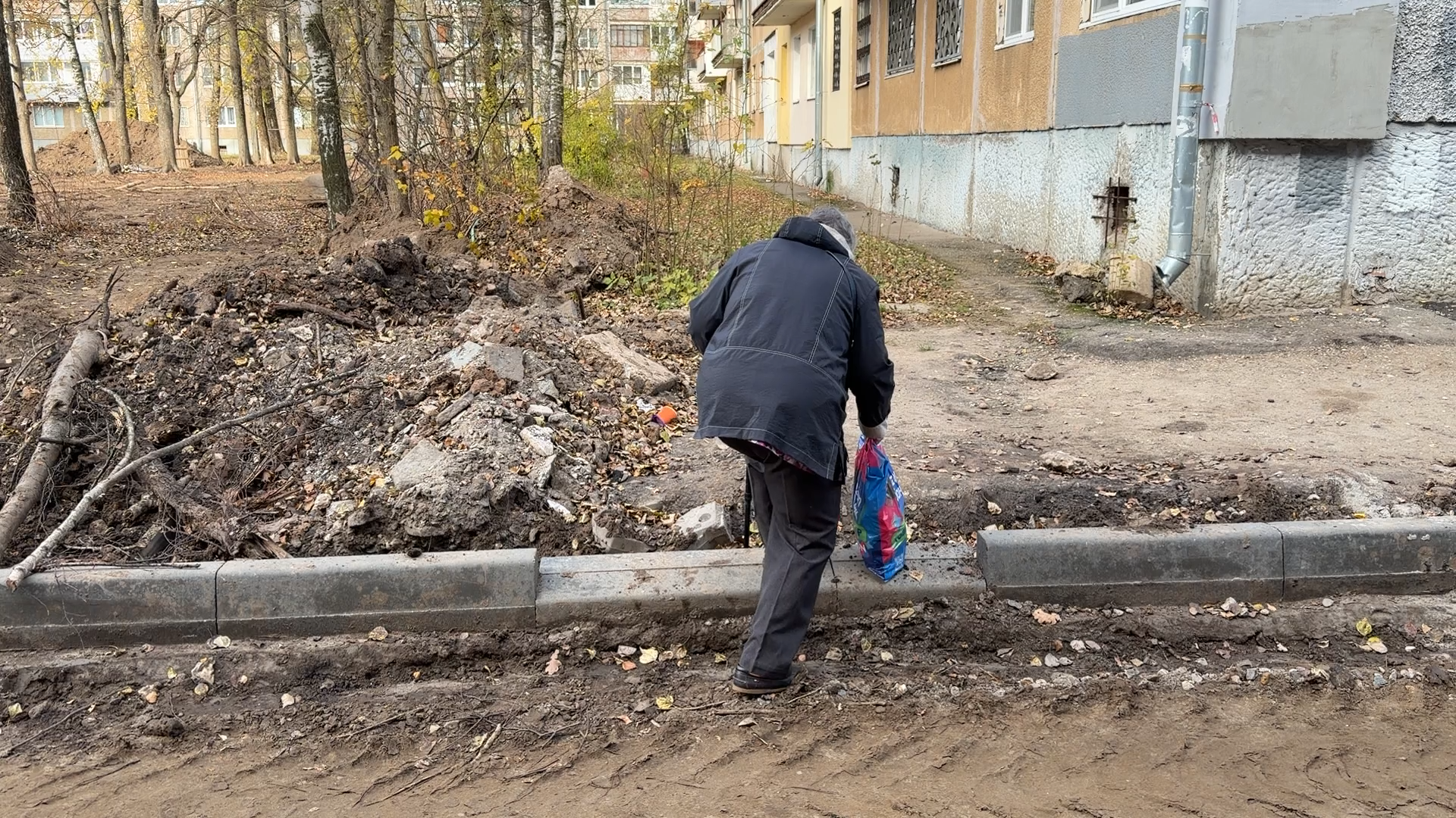 Жительница идёт через грязь и строительный мусор во дворе Ярославля
