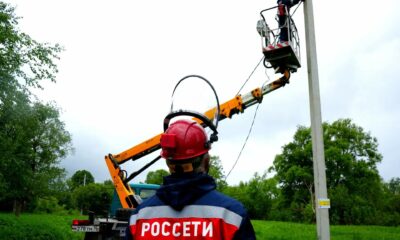 Энергетик Россети наблюдает за работой коллеги на автовышке у опоры линии электропередачи