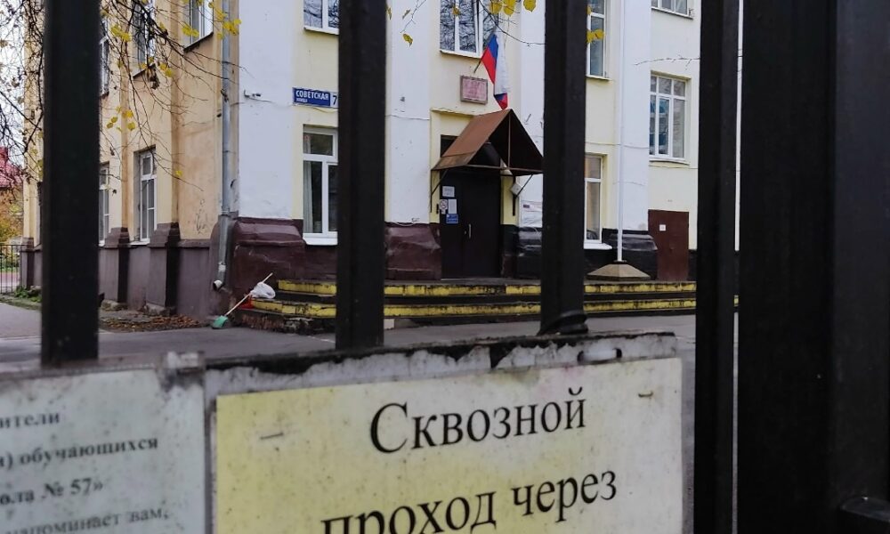 Здание школы за чёрными воротами с табличкой о закрытом сквозном проходе