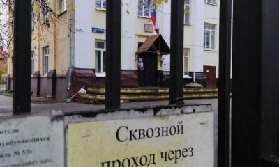 Здание школы за чёрными воротами с табличкой о закрытом сквозном проходе