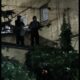 Двое людей в капюшонах стоят ночью на выступе у стены жилого дома