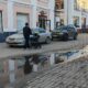 Мужчина везёт детскую коляску по тротуару рядом с припаркованными автомобилями