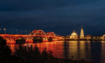 Волжский мост в Рыбинске с красно-золотой подсветкой ночью над рекой