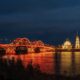 Волжский мост в Рыбинске с красно-золотой подсветкой ночью над рекой