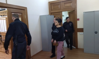 Женщину в сопровождении сотрудников полиции ведут по коридору суда